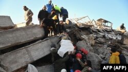 Спасатели несут раненого мужчину во время поисковых операций в городе Кахраманмараш на юго-востоке Турции