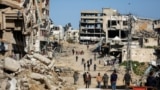 Жители сектора Газа идут по району Газы, разрушенному в ходе военной операции Израиля против боевиков ХАМАС, 20 марта 2024 года