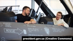 Президент Украины Владимир Зеленский и премьер-министр Дании Мэтте Фредериксен сидят в истребителе F-16 на авиабазе Скридструп в городе Военс, Дания, 20 августа 2023 года