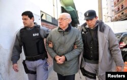 Бывший аргентинский диктатор Хорхе Рафаэль Видела в наручниках под конвоем полиции, которая сопровождает его в суд города Сан-Мартин в провинции Буэнос-Айрес, июль 2012 года. Фото: Reuters