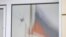 A Russian flag is seen reflected on a damaged window following fresh aerial attacks in the settlement of Razumnoye