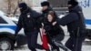 Полицейские задерживают женщину возле мемориала "Стена скорби" в Москве, куда люди несут цветы, свечи и фотографии в память об Алексее Навальном. 17 февраля 2024 года