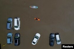 Жители Монпелье, штат Вермонт, на каноэ и падлборде проплывают мимо затопленных машин. 11 июля 2023 года. Фото: Reuters