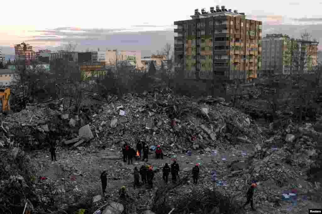 Люди собираются вокруг костра возле обломков дома в Кахраманмарасе, Турция, 15 февраля 2023 года.