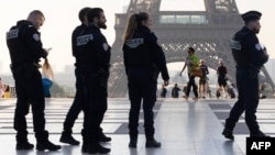 Офицеры французской национальной полиции перед Эйфелевой башней после установки на ней олимпийских колец к предстоящим Играм 2024 года в Париже, 7 июня 2024 года, фото AFP