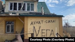 Один из разрушенных домов в Мариуполе, на фасаде дома надписи, оставленные, предположительно, российскими военными. Фото сделано в марте 2023 года