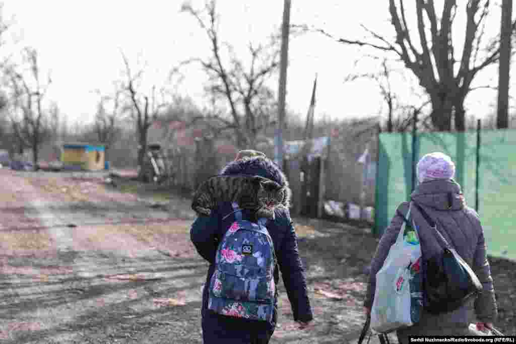 Кот сидит на плече ребенка, которого вместе с мамой эвакуируют из села Рудницкое, Киевщина, март 2022 года / Справа: та же улица в марте 2024 года