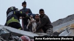 Сотрудники службы чрезвычайных ситуаций и волонтеры спасают ребенка после удара армии РФ по жилому многоэтажному дому в Славянске Донецкой области, 14 апреля 2023 года