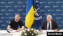 Генпрокурор Украины Андрей Костин и секретарь Международного уголовного суда Питер Льюис подписывают соглашение об открытии украинского представительства МУС