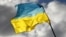 U.K. – Ukrainian personnel hold a Ukrainian flag as they stand on a Challenger 2 tank during training at Bovington Camp, near Wool in southwestern Britain, February 22, 2023
