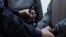 RUSSIA -- A police officer  puts the handcuffs on Russian former economy minister Alexei Ulyukayev 
