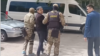 Kazakhstan -- People in camouflage uniforms are leading Aidar Syzdykov, clasping his arms, towards an unmarked bus. Astana, 16May2024