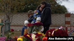 Родственники погибших во время ракетного удара по селу Гроза Харьковской области у импровизированного мемориала на месте трагедии