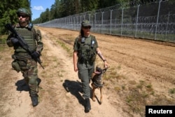 Член Союза стрелков Литвы и офицер пограничной службы патрулирует границу с Беларусью в Канюкае, Литва, 7 июля 2023 года, фото Reuters
