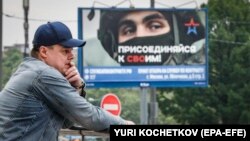 Москва, май 2023 года. Мужчина стоит на фоне плаката с призывом присоединяться к контрактной армии. Фото: EPA-EFE