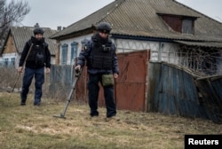 Саперы обследуют населенный пункт в Харьковской области, 21 марта 2023 года. Фото: Reuters