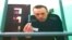 Russia -- Russian opposition leader Alexei Navalny is seen on a TV screen as he appears in a video link provided by the Russian Federal Penitentiary Service from the colony in Melekhovo