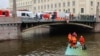 First responders operate at the site where a bus fell off the Potseluyev Bridge into the Moyka River