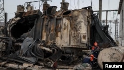 Работники Укрэнерго осматривают высоковольтный трансформатор, уничтоженный в ходе российского удара.