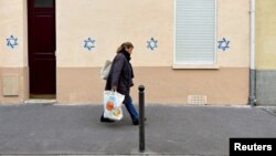Жительница Парижа идет мимо дома, на который неизвестные нанесли звезды Давида; антисемитские граффити стали появляться в некоторых европейских городах после начала войны
