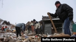 Местные жители убирают мусор на месте разрушенного в результате ракетного удара дома в Харьковской области, Украина, 8 января 2024 года