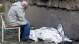 Дедушка сидит рядом с накрытым телом 9-летней внучки возле поликлиники, в которой находится бомбоубежище. Во время ракетного удара оно было закрыто, и люди не смогли туда попасть. Киев, Украина, 1 июня 2023 года 