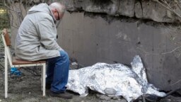 Дедушка сидит рядом с накрытым телом 9-летней внучки возле поликлиники, в которой находится бомбоубежище. Во время ракетного удара оно было закрыто, и люди не смогли туда попасть. Киев, Украина, 1 июня 2023 года 