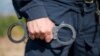 Detail of a police officer holding handcuffs. Selective focus with shallow depth of field.