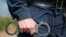 Detail of a police officer holding handcuffs. Selective focus with shallow depth of field.