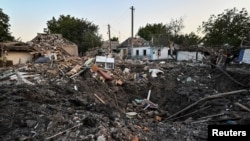 Люди стоят рядом с жилым домом, разрушенным в результате российского военного удара, Чаплино, Днепропетровская область, Украина, 24 августа 2022 года