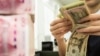 CHINA -- A Chinese bank employee counts 100-yuan notes and US dollar bills at a bank counter in Nantong in China's eastern Jiangsu province, August 6, 2019