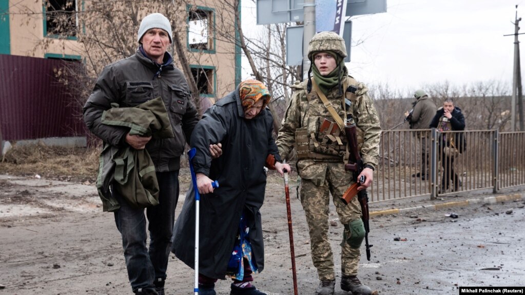 Украинские военнослужащие помогает эвакуироваться пожилой женщине в городе Ирпень Киевской области