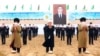 Туркменские старейшины и чиновники на фоне изображения президента Сердара Бердымухамедова, который занял пост в марте 2022 года вместо отца. Портреты Сердара и Гурбангулы Бердымухамедовых висят повсюду, их нет "разве что в туалетах"