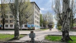 Люди идут мимо упавшей ракеты в городе Рубежное Луганской области 21 апреля 2022 года