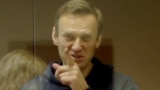 RUSSIA -- Russian opposition leader Aleksei Navalny, charged with defaming a World War II veteran, gestures from inside a glass cell during a court hearing in Moscow, February 16, 2021