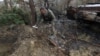 Военный сапер подбирает неразорвавшиеся части кассетной бомбы недалеко от села Мотыжин, Киевская область, Украина, 10 апреля 2022 года