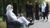 Девушка в защитном костюме сидит на скамейке на одной из улиц города.