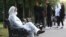 Девушка в защитном костюме сидит на скамейке на одной из улиц города.