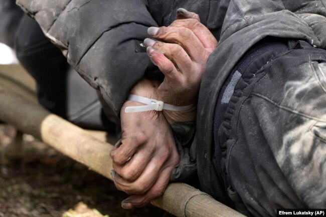 Связанные стяжкой руки убитого мирного жителя Бучи. 4 апреля 2022 года. Фото: AP