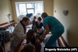 Врачи и сотрудники больницы переносят пациента. Городская больница Изюма через несколько дней после деоккупации, 17 сентября 2022 года. Фото: Евгений Малолетка, AP