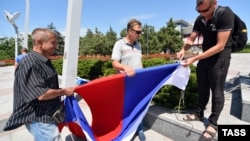 Мужчины готовятся повесить российский флаг в оккупированном Мариуполе. Украина, Донецкая область. 11 июня 2022 года