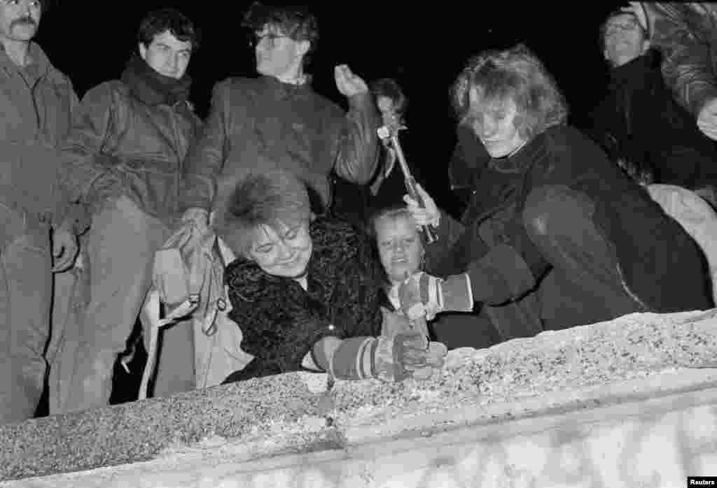 Жители Берлина разбирают Берлинскую стену напротив Бранденбургских ворот. 9 ноября 1989 