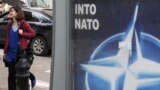 Georgia -- A young woman walks past a poster bearing the NATO logo in Tbilisi, 06May2009