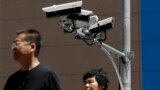 China US Trade - People walk by Chinese-made surveillance cameras installed along a street in Beijing, Thursday, May 23, 2019. The Chinese video surveillance company Hikvision says it is taking concern about the use of its technology seriously following a
