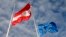 An Austrian and a European flag flutter in the wind at the Austrian embassy underneath an in Berlin