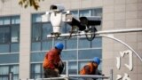 China - Men work on top of a scaffolding underneath CCTV surveillance cameras in Beijing