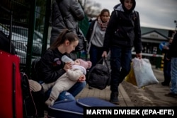 Женщина кормит ребенка на пограничном переходе Убла в Словакии, 25 февраля 2022 года
