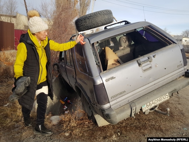 Лаура Нургалиева показывает обстрелянную машину, в которой в Талдыкоргане погиб ее муж