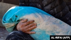 Мужчина несет тело своего ребенка, извлеченное из-под завалов в городе Харим на северо-западе Сирии