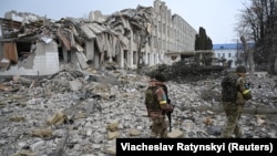 Украинские военные идут мимо разрушенной школы в Харькове. Март 2022 года